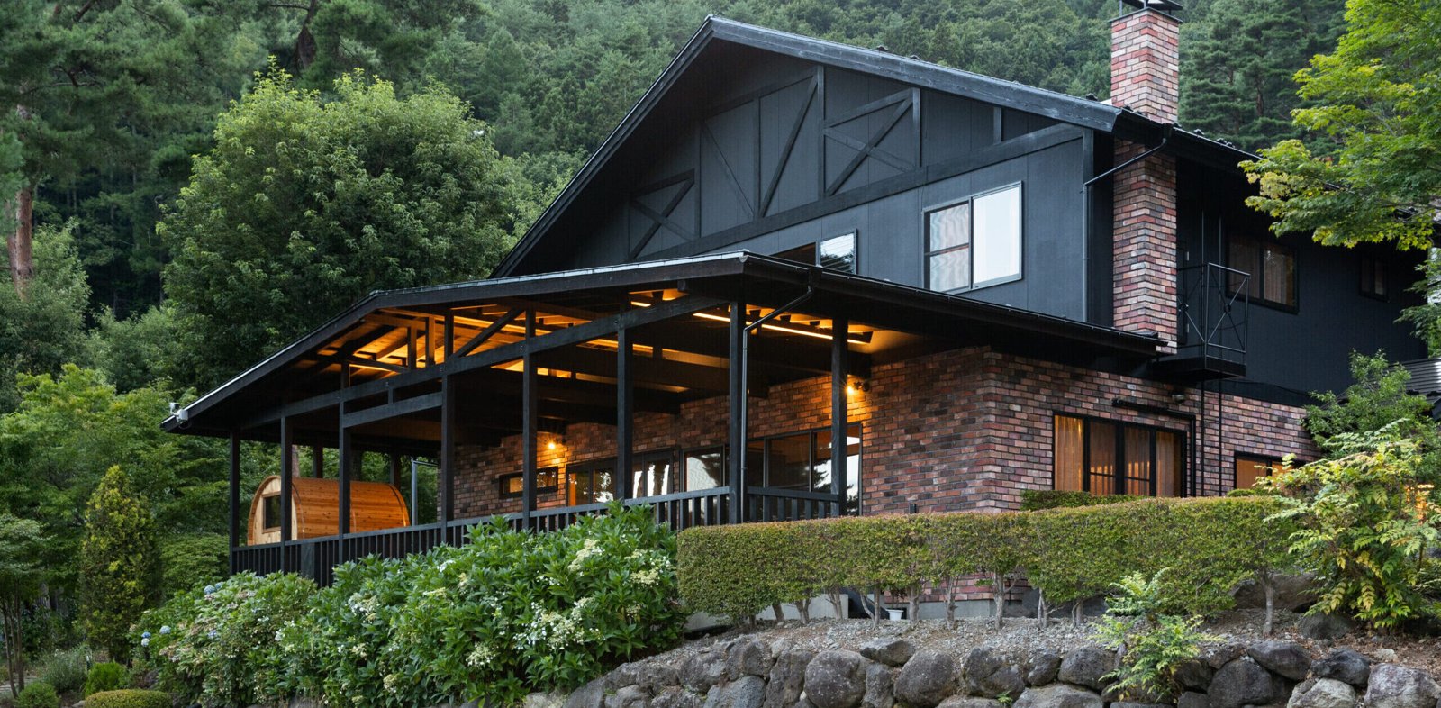 河口湖カントリーコテージBan — 山梨・富士河口湖町 · 森に囲まれた黒い外壁のコテージ、屋根付きテラス付き