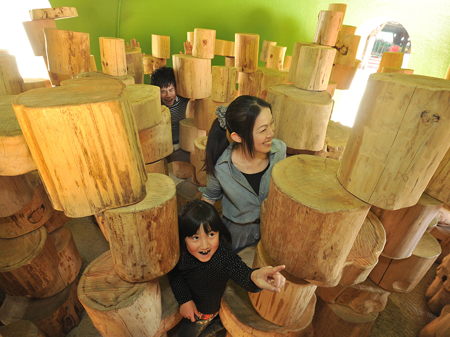 阿蘇ファームランド — 熊本県南阿蘇村 · 元気の森の丸太を積み上げた遊具で遊ぶ親子、対象年齢4歳以上