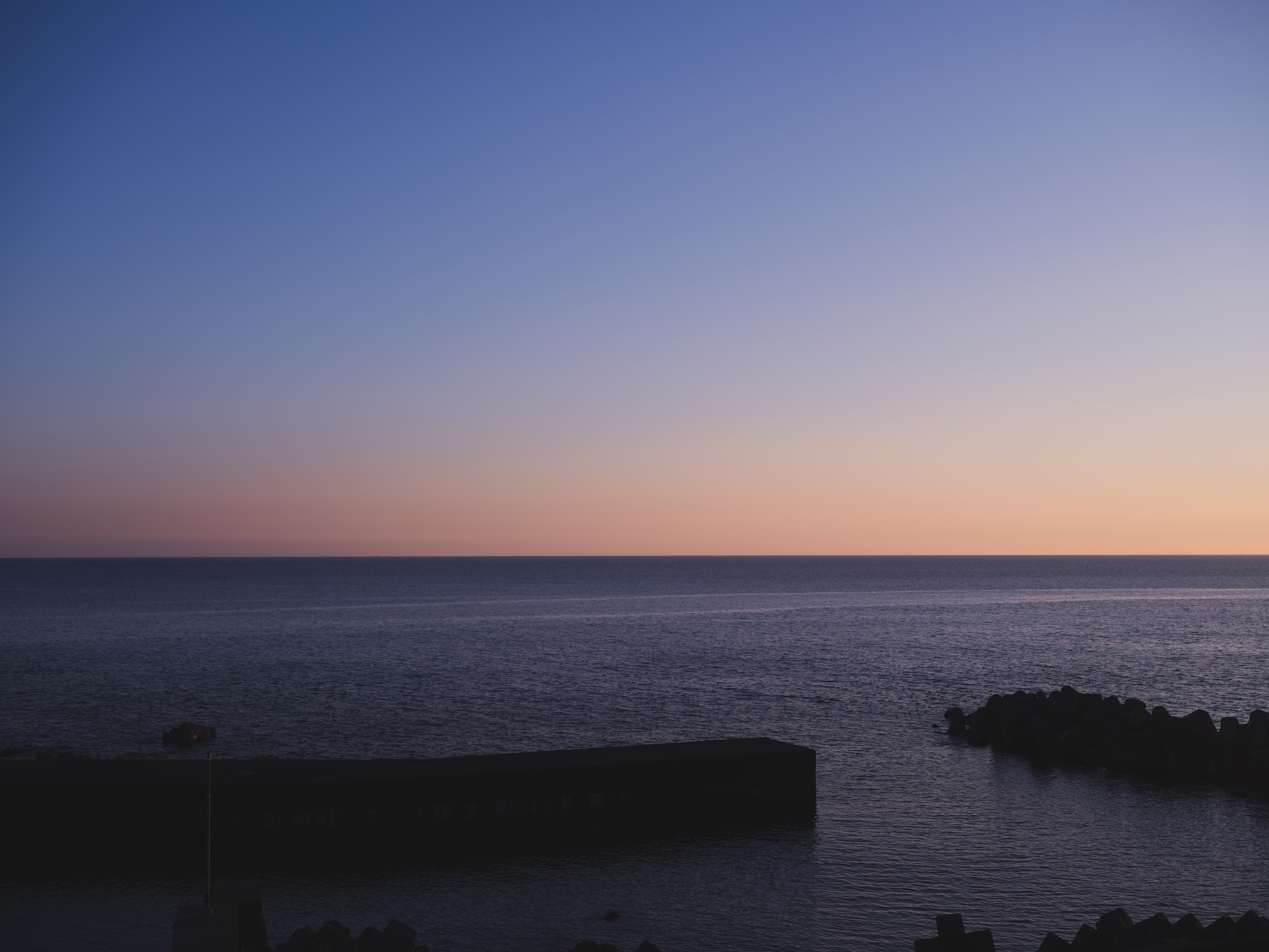 料理旅館 かねとも — 福井県越前町厨 · 夕暮れの日本海と防波堤を望む越前海岸の宿からの眺め