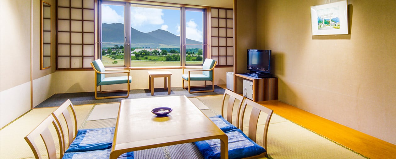 休暇村 蒜山高原 — 岡山県真庭市 · 蒜山三座を正面に望む和室、畳に座卓と広縁の椅子