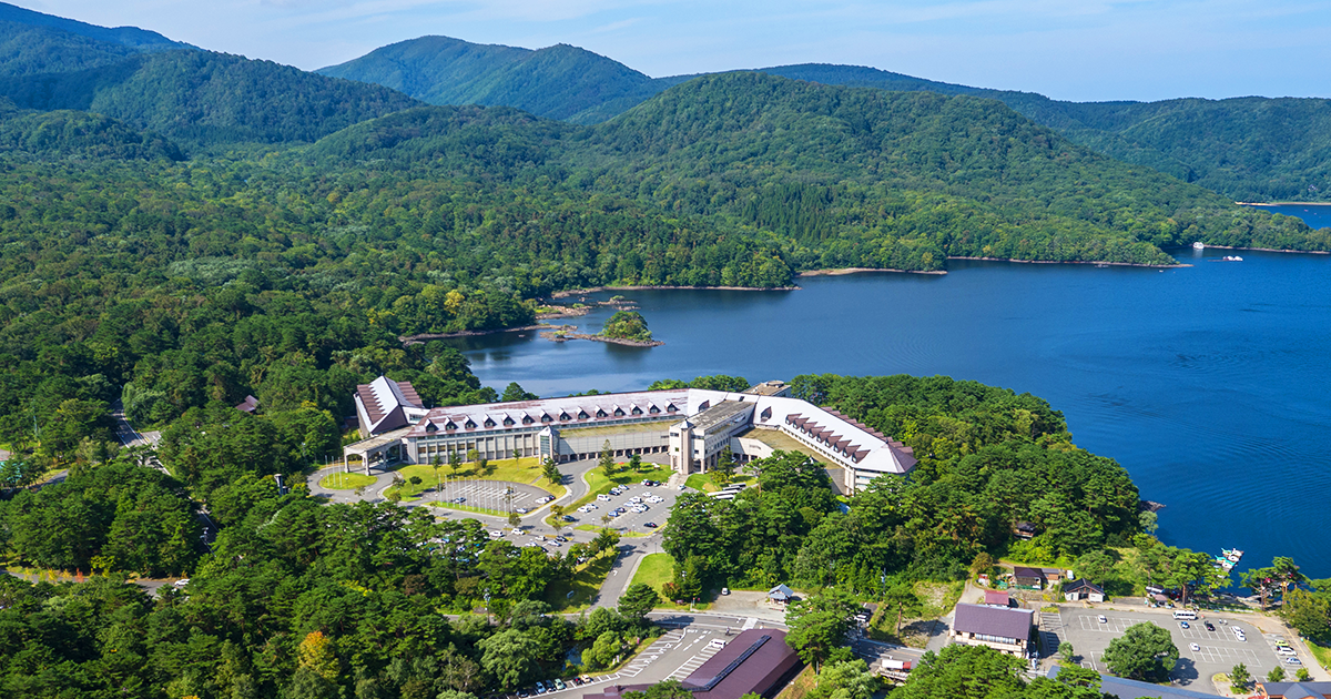裏磐梯レイクリゾート — 福島県北塩原村 · 桧原湖畔の森に建つ本館「五色の森」を上空から望む