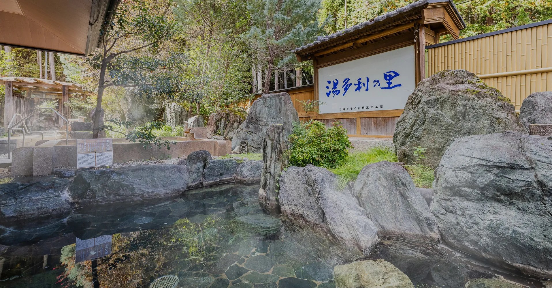 湯多利の里 伊那華 — 阿智村昼神温泉・岩を組んだ庭園露天風呂と「湯多利の里」の看板