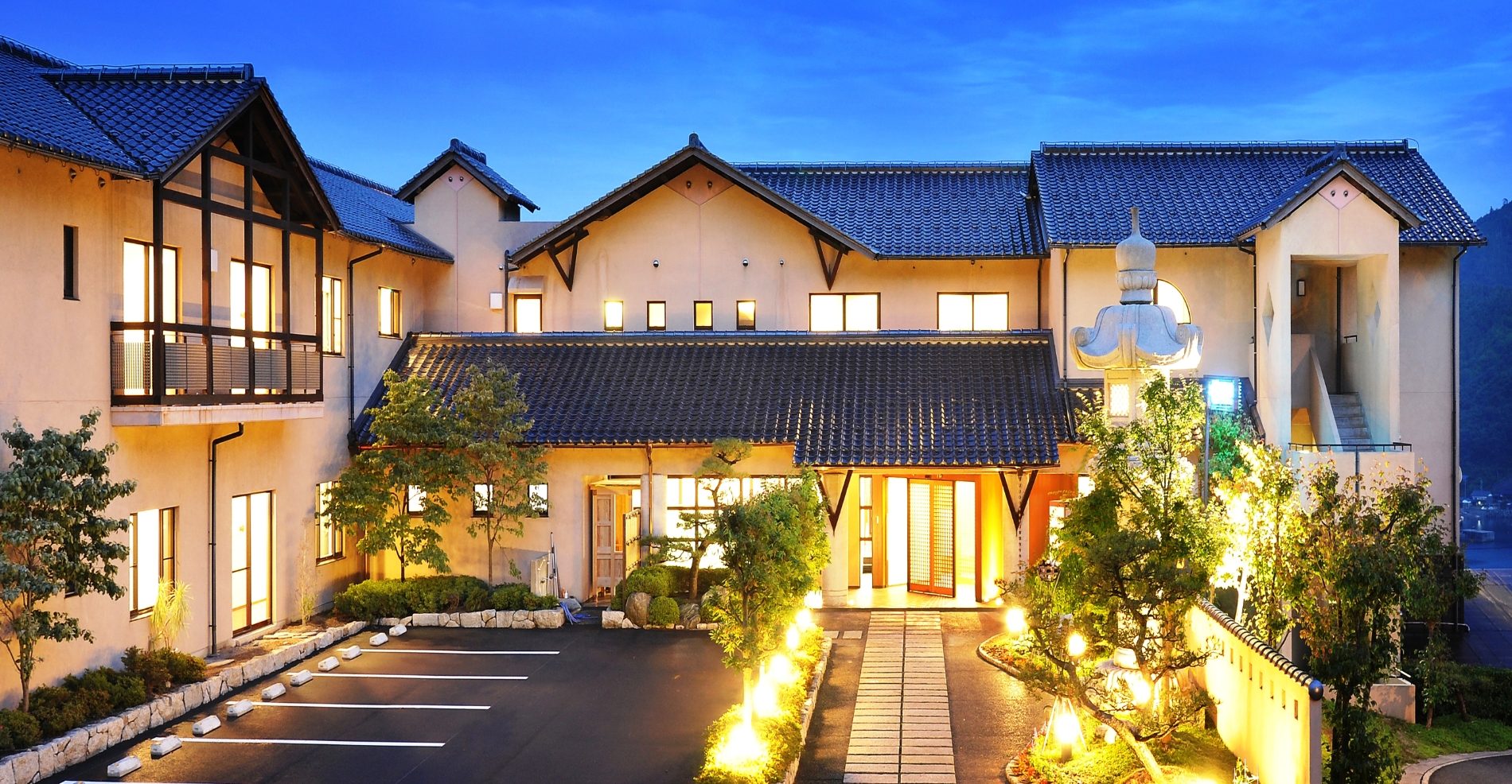 奥伊根温泉 油屋本館 — 伊根町津母 · 夕暮れにライトアップされた洋館風の外観と前庭