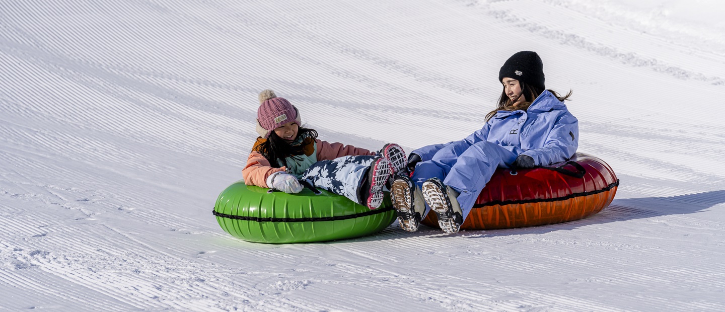 ルスツリゾートホテル＆コンベンション — 北海道留寿都村 · ルスツリゾートの雪上でチュービングを楽しむ親子