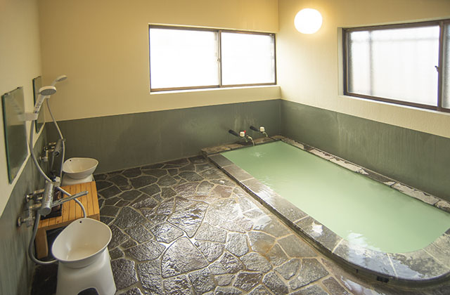 永田屋 昭和館 — わたの湯源泉かけ流しの内湯 · 石張りの洗い場に2か所のシャワー