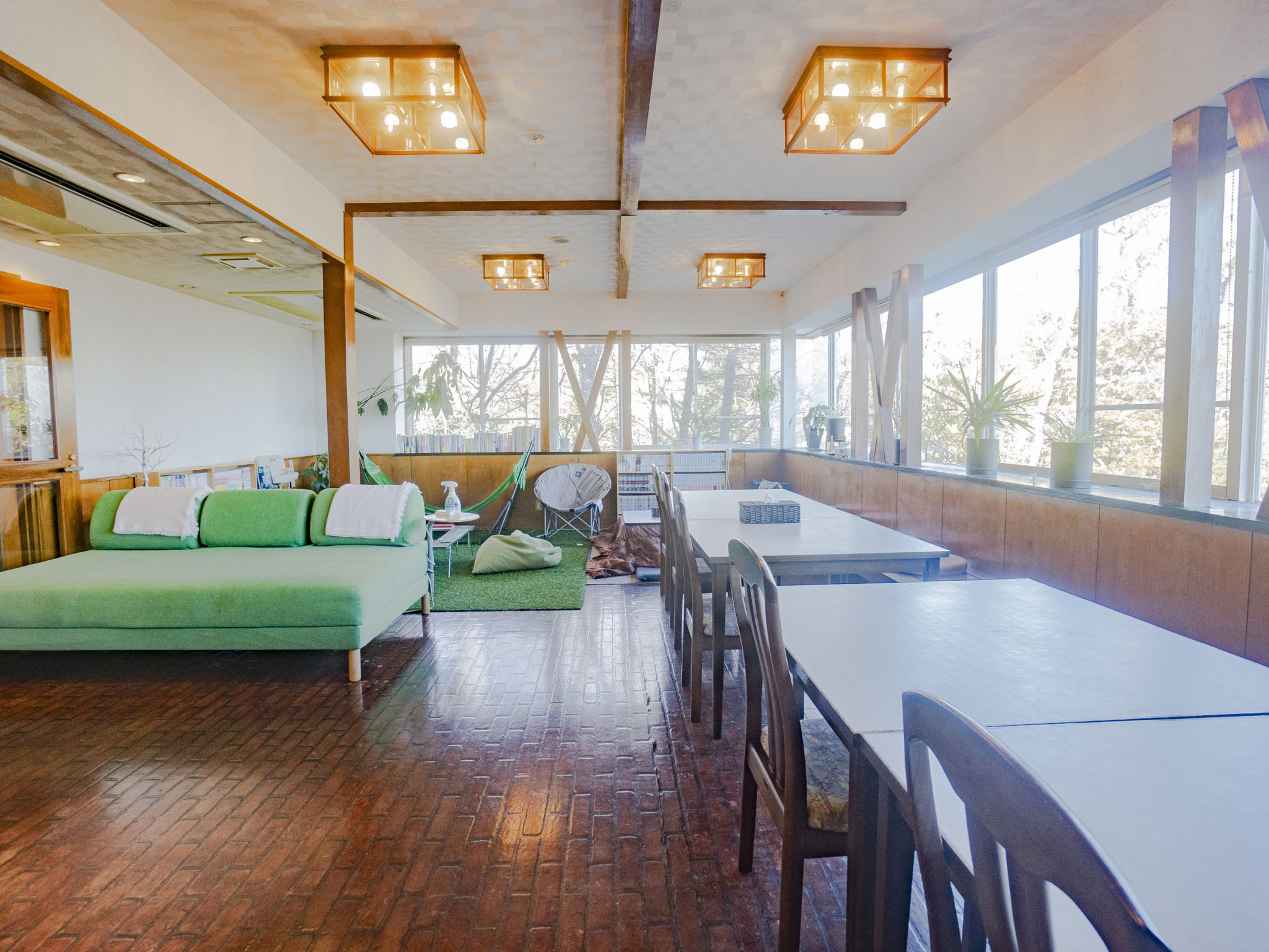 We Home Villa 城ケ崎温泉 — 静岡県伊東市八幡野 · 長テーブルとソファ、人工芝の遊び場を備えた共用ラウンジ