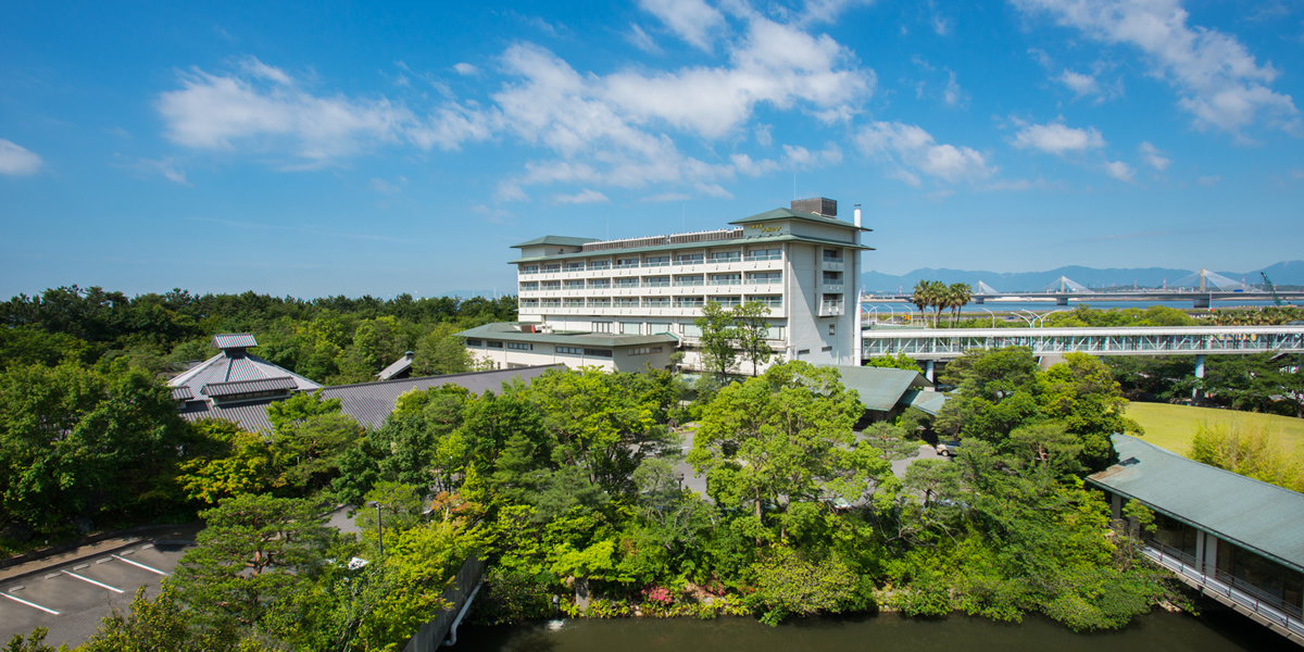 ホテルナガシマ — 三重県桑名市・長島温泉 · 緑の庭園の奥に建つ客室棟と遊園地方面への連絡通路