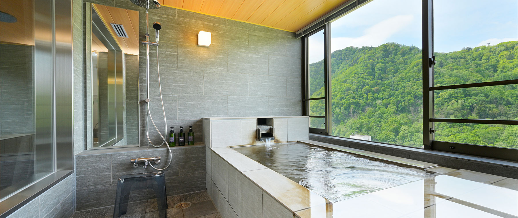 定山渓万世閣ホテルミリオーネ — 札幌市南区定山渓温泉 · 山の緑を望む窓辺の浴槽