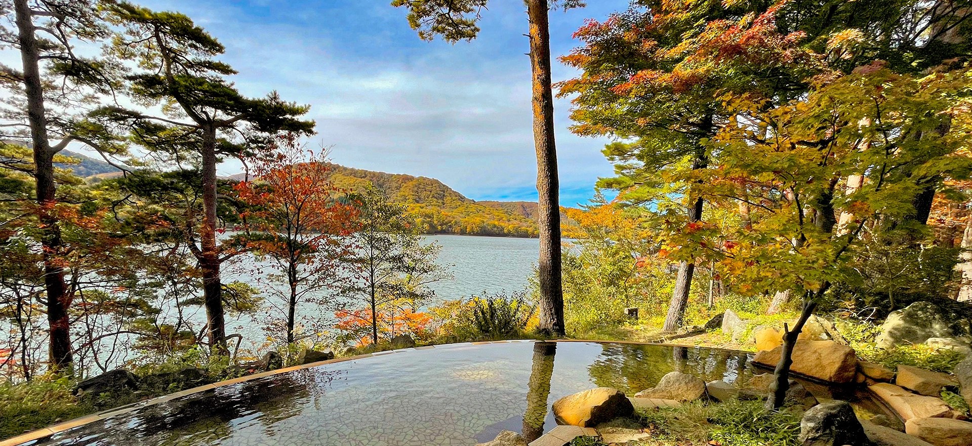 裏磐梯レイクリゾート 五色の森 — 福島県北塩原村・桧原湖畔 · 紅葉の木立越しに桧原湖を望む露天風呂