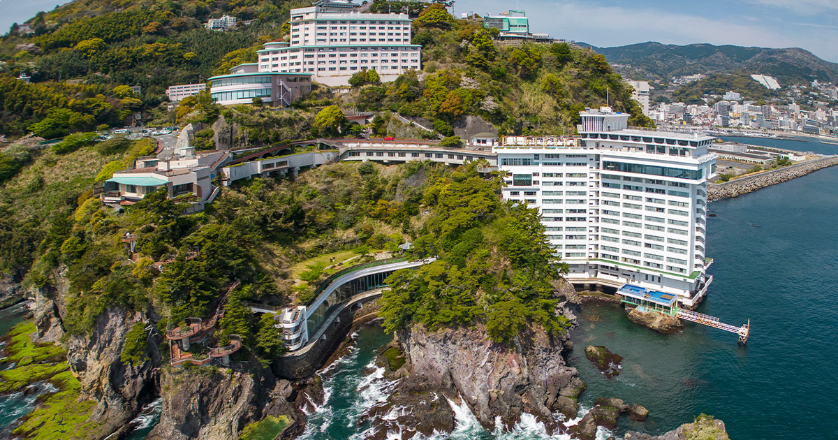 ホテルニューアカオ — 静岡・熱海 · 錦ヶ浦の岬に建つ2棟のホテルを海側から見た全景